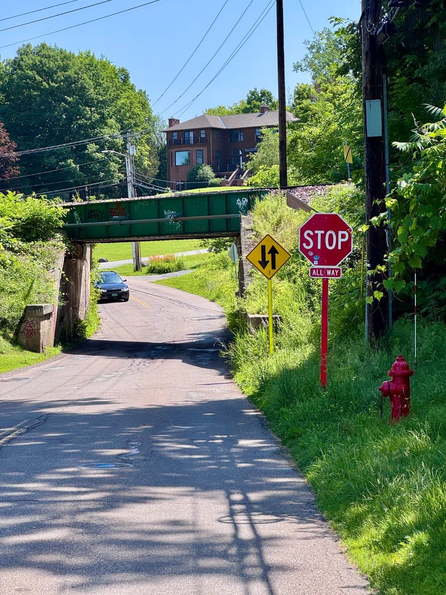 The railroad underpass on Bay Road, narrowing to a single all-way-stop lane beneath the trestle